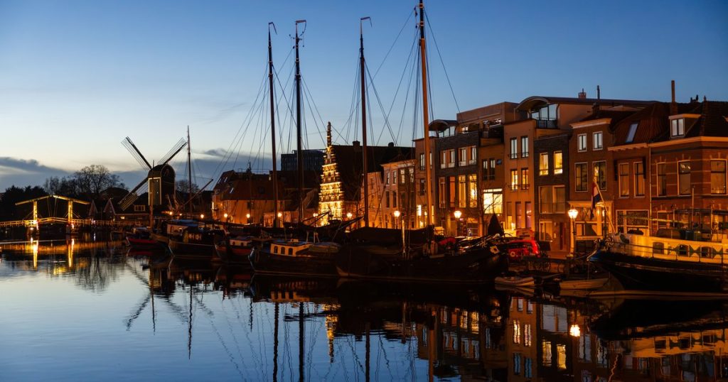 Avondbeeld van een Leidse gracht met boten en traditionele bebouwing