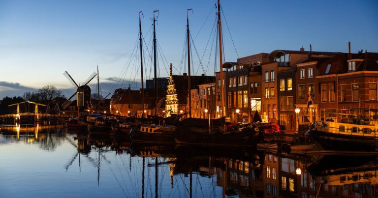 Avondbeeld van een Leidse gracht met boten en traditionele bebouwing