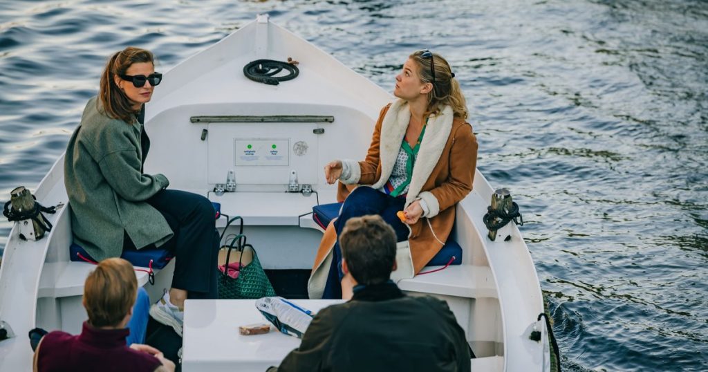 Houten sloep die rustig aanlegt langs een houten steiger in kalm Nederlands binnenwater op een zonnige dag