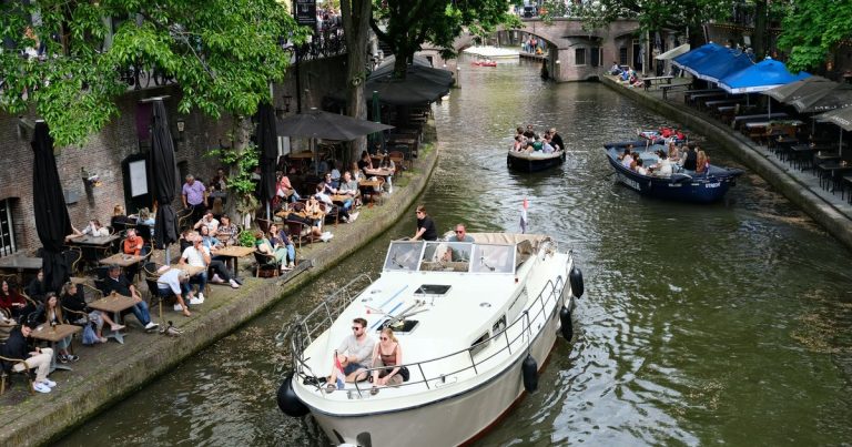 Boten varen door een Utrechtse gracht met terrassen langs de kade