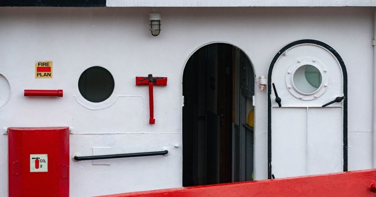 Open schutsluis met een houten sloep die rustig naar binnen vaart tussen de groene sluisdeuren in een Hollands kanaal