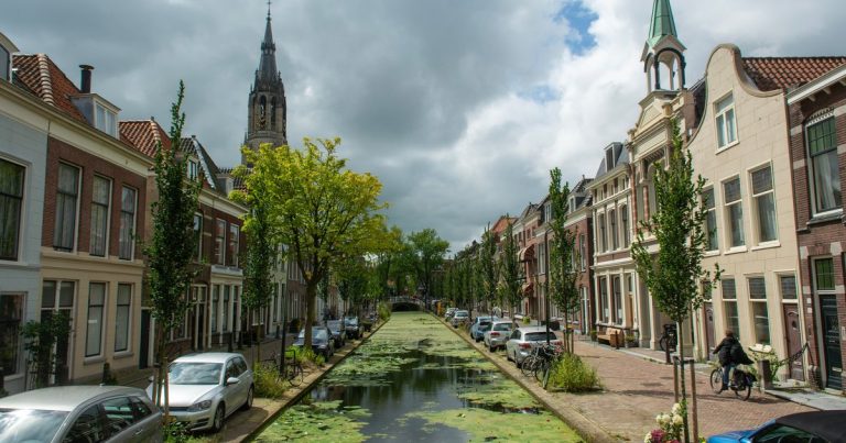 Een gracht in Delft met historische panden onder een bewolkte lucht