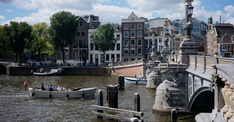 Boten op een Amsterdamse gracht bij een historische brug, startpunt van de sloeproute over de Amstel naar Ouderkerk aan de Amstel