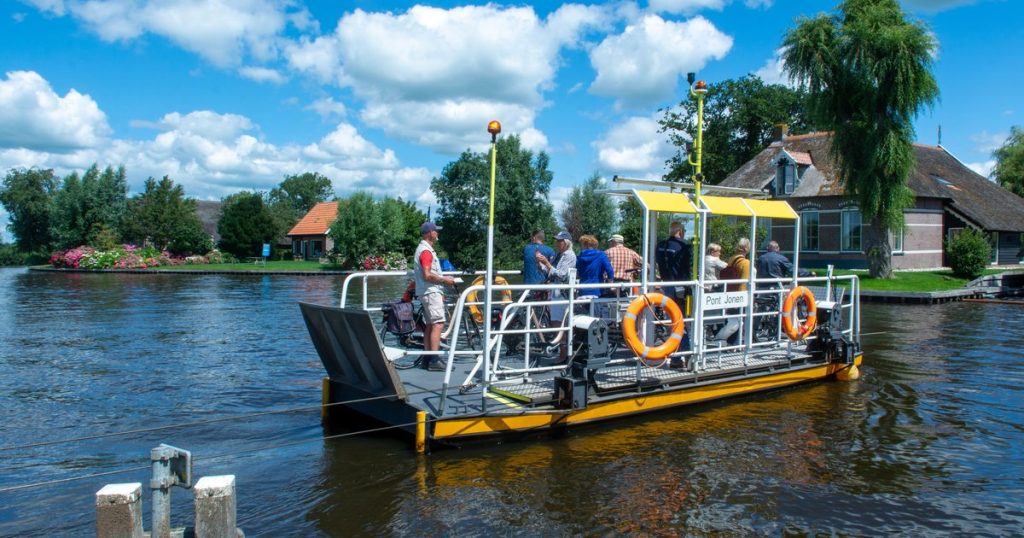 Een veerpontje met passagiers steekt op een zonnige zomerdag het water over