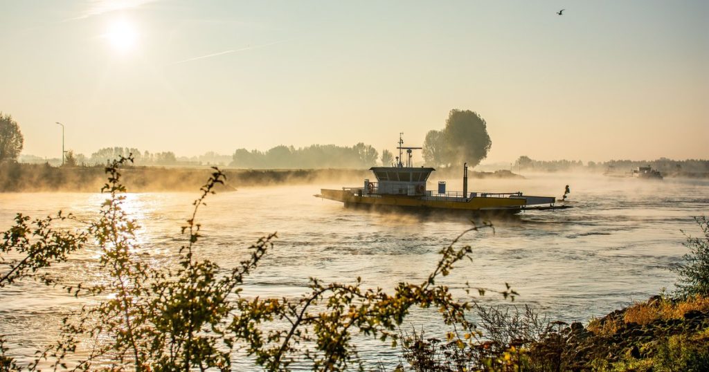 Een pontje steekt in de vroege ochtend een mistige rivier over