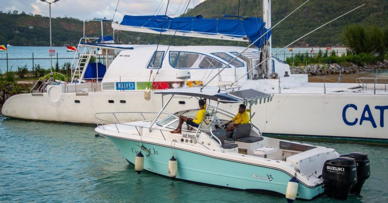 Twee boten voor anker in een tropische jachthaven met heuvels op de achtergrond.