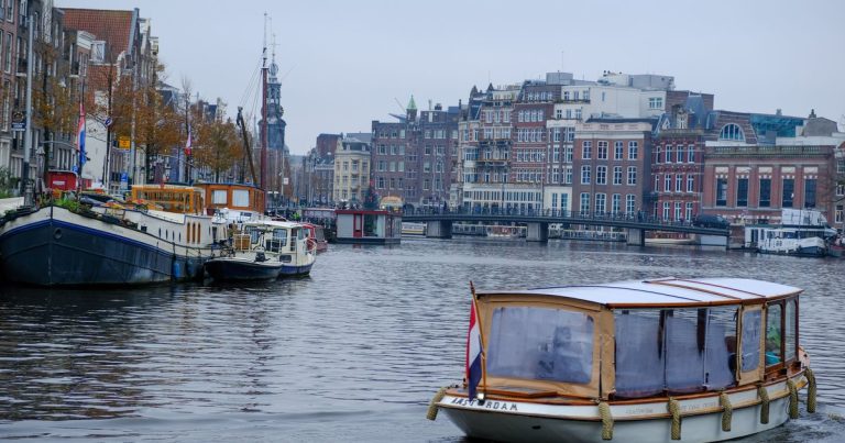 Ontdek de schilderachtige grachten van Amsterdam met traditionele boten en historische gevels langs het water.