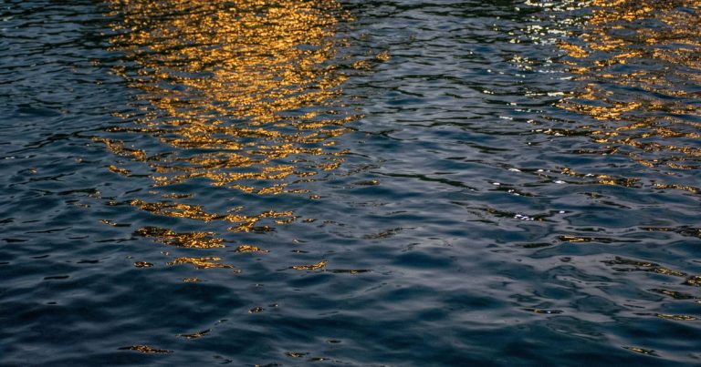Avondlichten weerspiegelen op een rustig wateroppervlak met een serene gouden gloed.