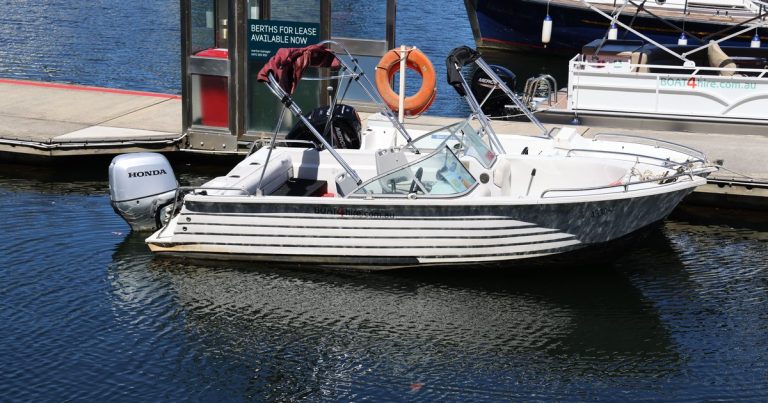Motorboot met Honda motor afgemeerd in een jachthaven bij fel zonlicht.