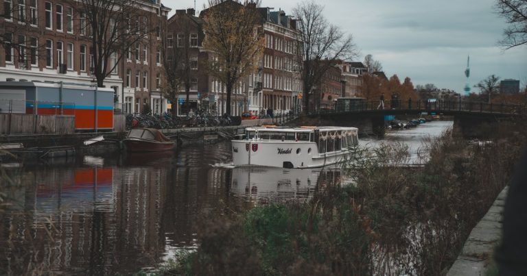 Amsterdamse gracht met een rondvaartboot, historische panden en herfstbomen