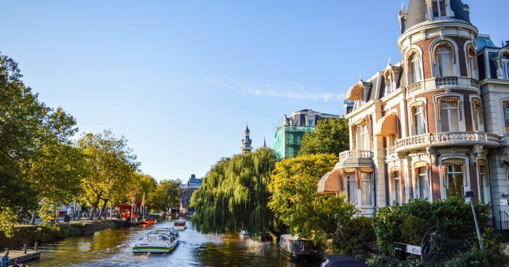 Schilderachtig uitzicht op een Amsterdamse gracht met historische architectuur en boten op een zonnige dag