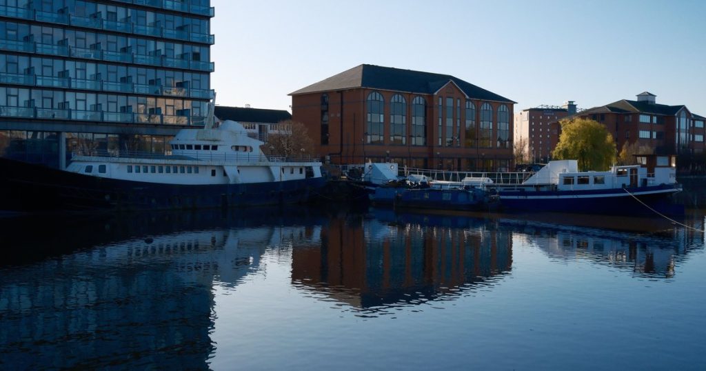 Boten afgemeerd langs moderne en klassieke gebouwen, weerspiegeld in rustig water