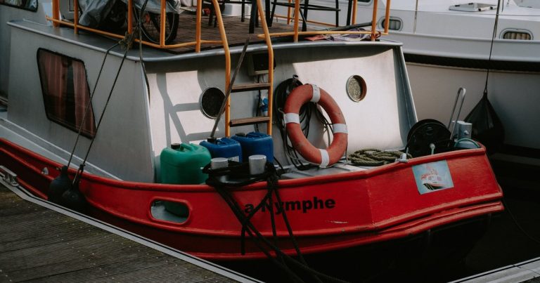 Een kleurrijke woonboot afgemeerd in een jachthaven, met reddingsboei aan dek