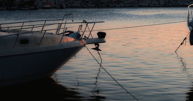 Voor anker liggende boten weerspiegeld in het water bij zonsondergang