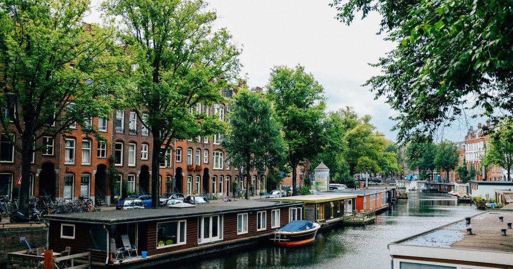 Een gracht met woonboten en bomen langs de kade