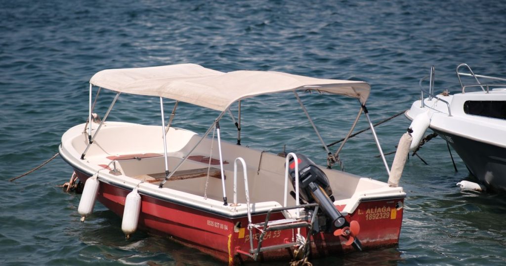 Een kleine vissersboot met zonnetent, afgemeerd aan rustig water