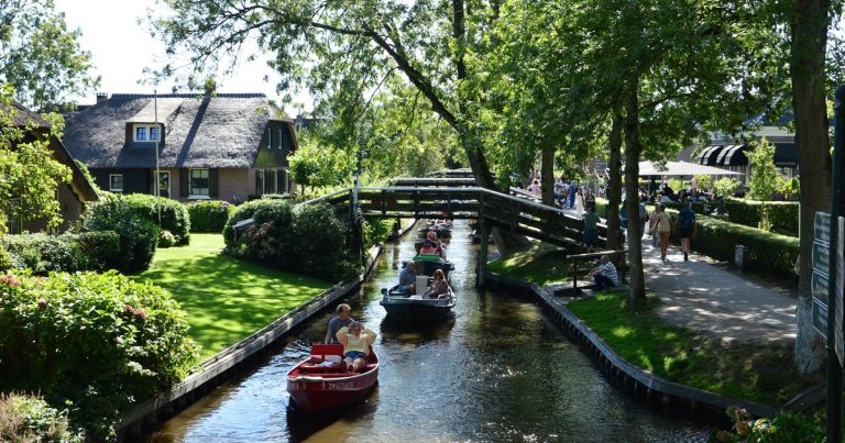 Boten varen door de smalle grachten van Giethoorn, tussen het groen