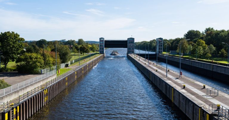 Een boot vaart op een zonnige dag door de sluisdeuren van een kanaal