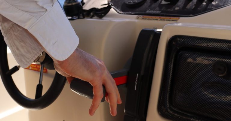 Een hand aan de gashendel op het stuurconsole van een boot