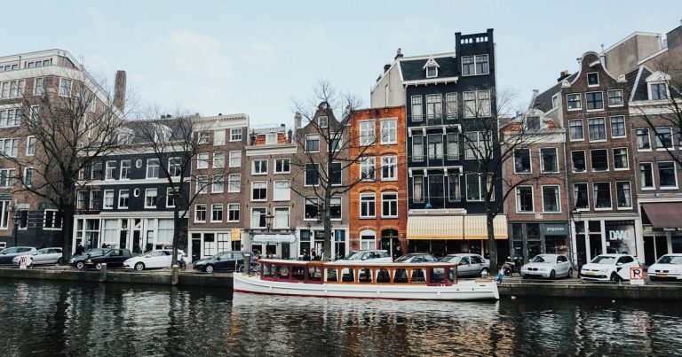 Een boot vaart door een Amsterdamse gracht langs klassieke grachtenpanden