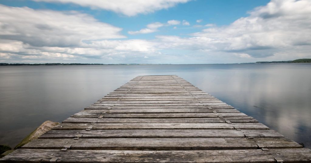 Een houten steiger die uitsteekt over stil water