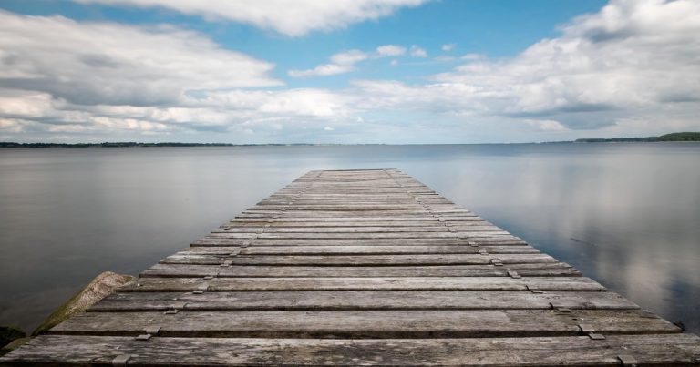 Een houten steiger die uitsteekt over stil water