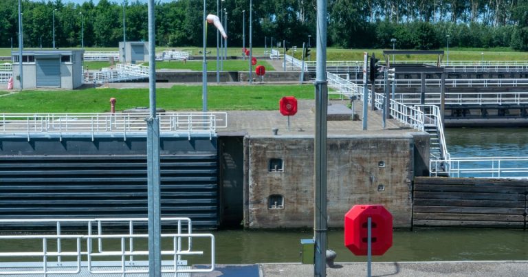 Een moderne sluis met sluisdeuren en veiligheidsboeien op een zonnige dag