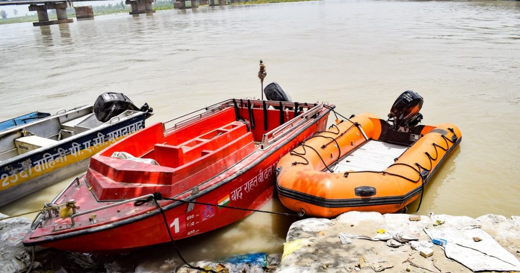 Rood en oranje gekleurde boten afgemeerd aan een rivier onder een stalen brug