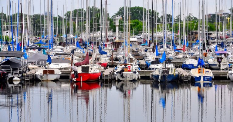 Een levendige jachthaven vol kleurrijke zeilboten en jachten, weerspiegeld in het kalme water