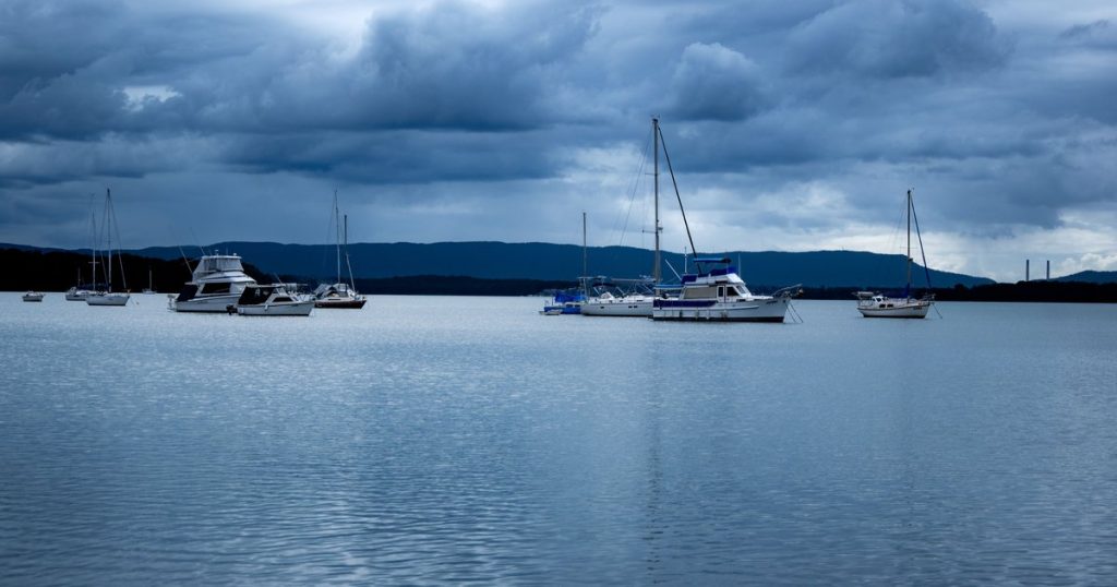 Kalm meer met aangemeerde zeilboten onder dramatische wolken