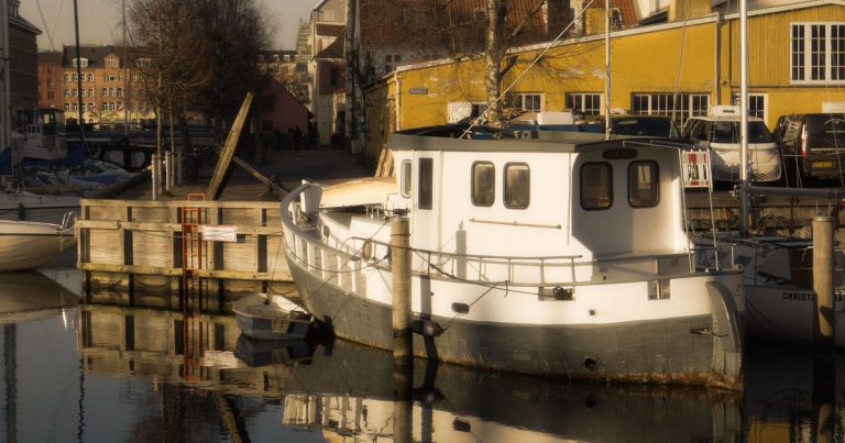 Rustig kanaal in Kopenhagen met boten die weerspiegelen in het water bij zonsondergang
