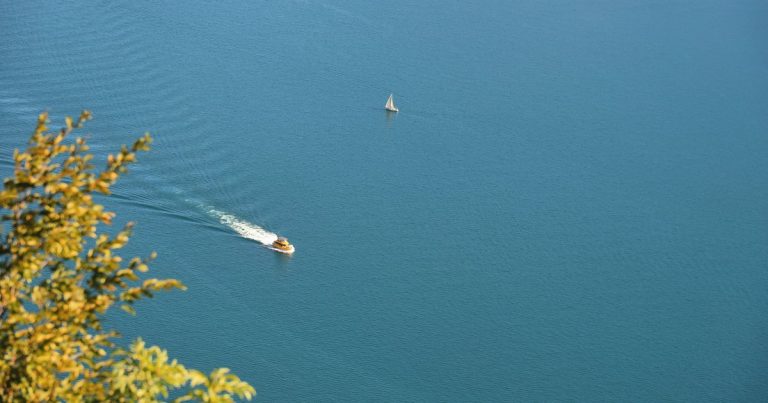 Luchtfoto van een motorboot en een zeilboot op het kalme water van het Gardameer, Italië.