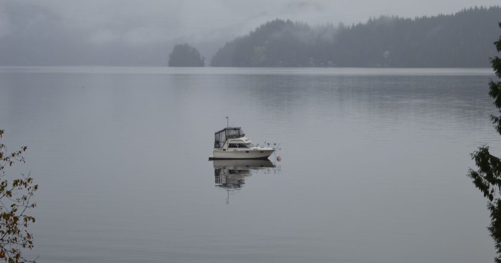 Eenzame boot drijft op een mistig meer in Brits-Columbia, omringd door kalm water en mist